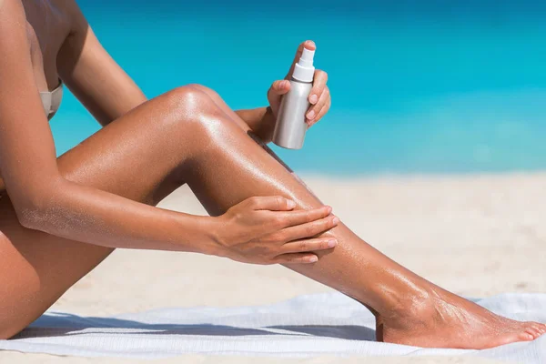 Mujer rociando crema solar crema bronceadora en la playa —  Fotos de Stock