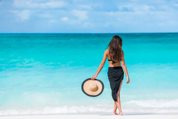 Žena v černých bikinách a sarong stojící na pláži — Stock fotografie