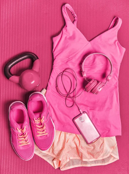 Activewear fitness clothes outfit - girly pink fashion sportswear clothing for girl training with kettlebell weights and phone headphones to listen to music during workout at gym. — Stock Photo, Image