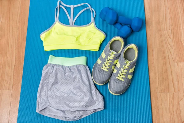 Fitness-Outfit auf Trainingsmatte mit Gewichten und Laufschuhen. Sport-BH und graue Shorts für das Training zu Hause. Style- und Mode-Aktivbekleidung. — Stockfoto