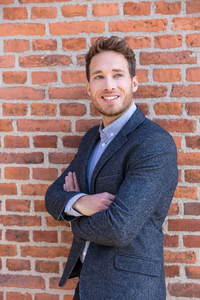Smart casual businessman on urban city brick wall background lifestyle portrait. Young professional man smiling confident in blazer. Career and entrepreneurship concept — Stock Photo, Image