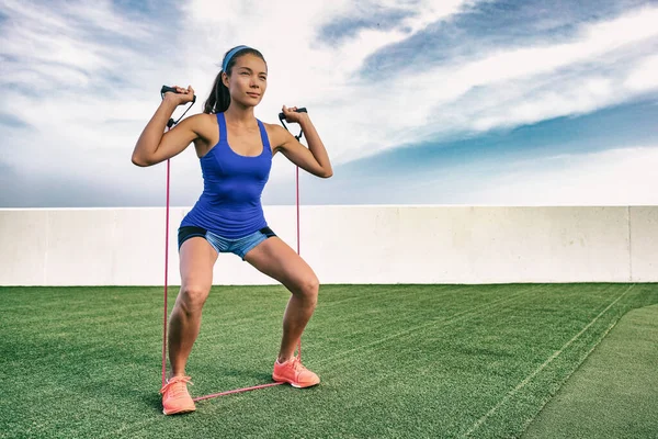 Esercizio donna con elastico fitness allenamento in palestra all'aperto. Ragazza asiatica che fa allenamento di resistenza all'esterno sull'erba. Adatto allo stile di vita. Squat e scapola con elastici — Foto Stock