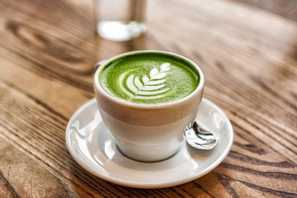 Matcha latte tasse de mousse de lait vert sur la table en bois au café. Tendance du thé alimenté à la mode du Japon — Photo