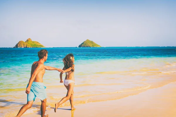 Casal de praia feliz no amor se divertindo correndo no verão Hawaii viagem de férias. Homem e mulher de mãos dadas no Sol. Lanikai, Oahu, EUA — Fotografia de Stock