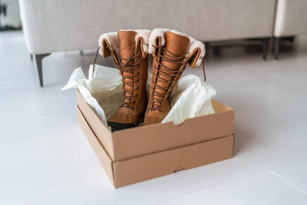 Nuevas botas de invierno que compran nuevos zapatos de senderismo en línea de compras y entrega. Caja de zapatos de apertura en la sala de estar en casa — Foto de Stock