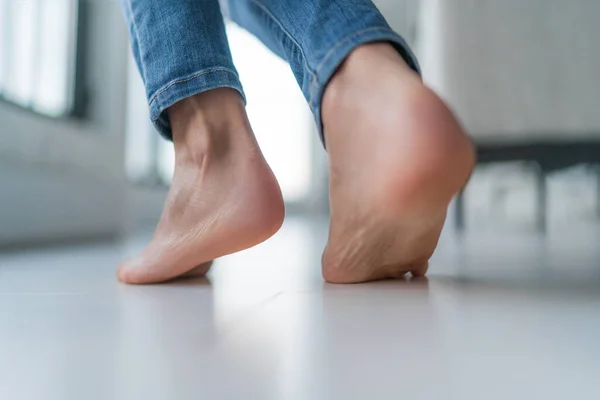 Piso de aquecimento mulher andando descalça no chão de madeira no inverno dentro de casa. Conforto estilo de vida sala. Fechar-se de pés de mulheres — Fotografia de Stock