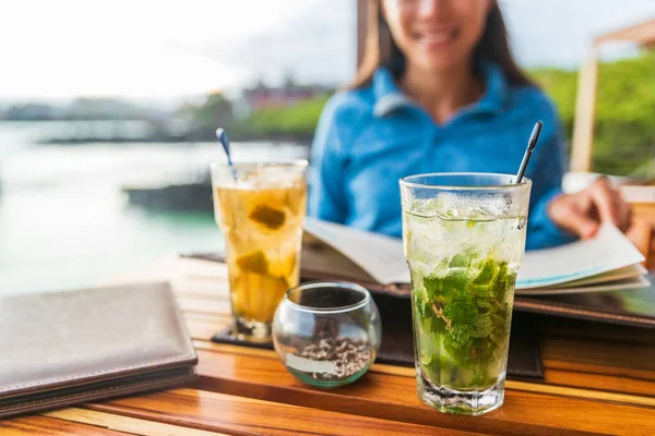 Dos cócteles alcohólicos en el restaurante de playa al aire libre en la mesa de comedor. Mujer y primer plano de bebida mojito cóctel — Foto de Stock