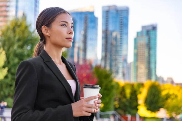 Mujer de negocios asiática driking taza de café fuera en el descanso de la oficina contemplativa pensativa mirando hacia otro lado en el fondo de la ciudad al aire libre. Estilo de vida de mujer de negocios — Foto de Stock