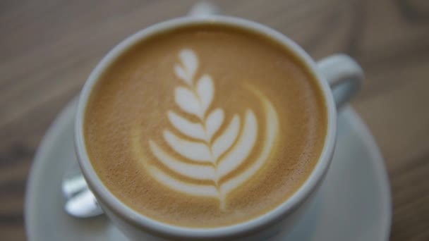 Café taza de capuchino de cerca vista superior con café latte arte en la cafetería — Vídeos de Stock