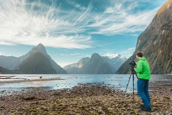Fotograf turystyczny robiący zdjęcia profesjonalnym aparatem fotograficznym na statywie na przygodowych wakacjach w górskim krajobrazie. Milford Sound, Park Narodowy Fiordland, Wyspa Południowa, Nowa Zelandia — Zdjęcie stockowe