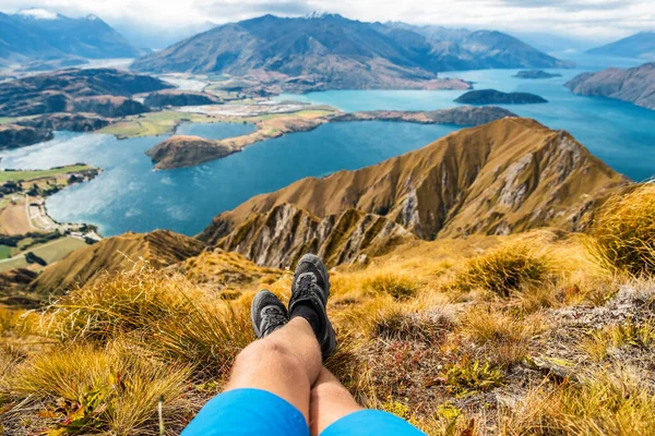 Dobrodružství a turistika wanderlust cestovní dovolená koncept s turisty pěší boty zblízka. Turista muž při pohledu na pohled ze slavné túry na Roys Peak na Jižním ostrově, Nový Zéland. Odpočinek a relaxace — Stock fotografie