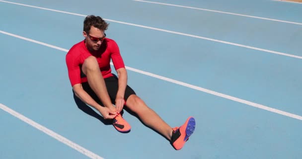 Sportowiec sprinter przygotowuje się do uruchomienia wiązanie sznurowadła buty na stadionie bieżni — Wideo stockowe