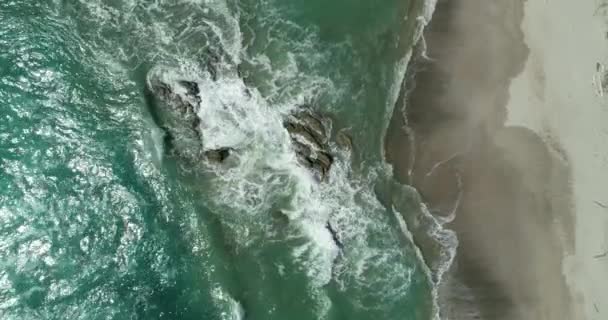 Vista aerea dall'alto delle onde oceaniche che si infrangono su una spiaggia. Onde marine e bella spiaggia di sabbia tiro drone vista aerea. Top down Vista a volo d'uccello delle onde dell'oceano che si schiantano sulla spiaggia di sabbia dall'alto. — Video Stock