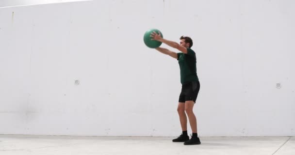 Medicijnbal Squat met bovenliggende schouder omhoog. Gewichtsoefeningen fitnessman trainen benen en billen met gewogen medicijnballen. Atleet aan het sporten in de sportschool — Stockvideo