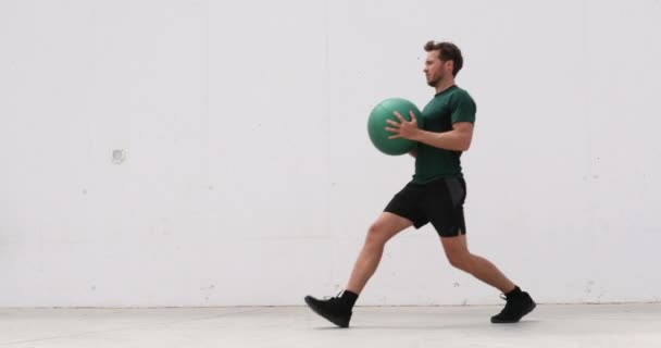 Trainen man training benen en kern buiktraining doen longtraining met medicijnbal gewicht. Gym atleet doet lunges voor benen training — Stockvideo