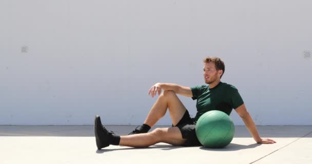 Homem atleta relaxando no ginásio de fitness durante o treino de bola de medicina. Estilo de vida saudável e ativo retrato adulto jovem — Vídeo de Stock