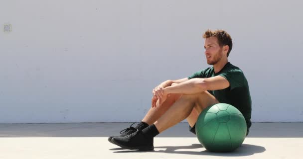 Fit athlete man relaxing at fitness gym during medicine ball workout. Healthy and active lifestyle young adult portrait — Stock Video