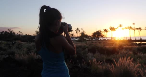 Kobieta robiąca zdjęcia na plaży Paradise zachód słońca z tropikalnymi palmami. Wakacje letnie wakacje wypad kolorowe pojęcie zdjęcie z morza ocean wody na plaży Waikoloa, Big Island, Hawaje, USA — Wideo stockowe