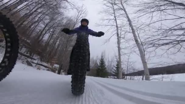 Fat bike in winter. Fat biker riding bicycle in the snow in winter. Close up action shot of fat tire bike wheels in the snow. Woman living healthy winter sports lifestyle. Shot on action camera. — Stock Video