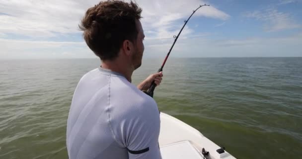 Людина рибалка в морі з човна кидає приманку кидаючи лінію — стокове відео