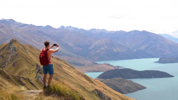 Путешественник фотографирует ландшафты с телефона на горе Новая Зеландия — стоковое видео