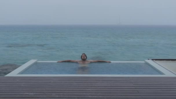 Vacation rain - funny video of man on in luxury pool while bad weather — Stock Video
