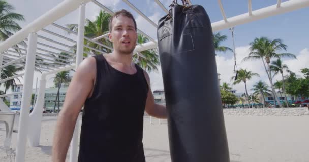 Retrato de homem fitness treinamento boxe perfurando saco pesado no ginásio ao ar livre — Vídeo de Stock