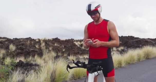 Phone app - triathlete man biking on triathlon bike using smartphone apps — Stock Video