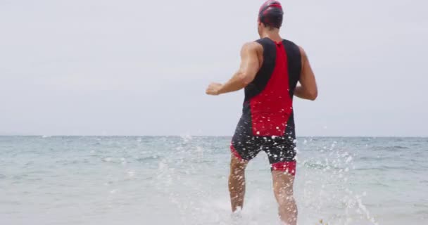 Hombre nadador de triatlón - nadador de triatleta masculino corriendo hacia el océano para nadar — Vídeo de stock