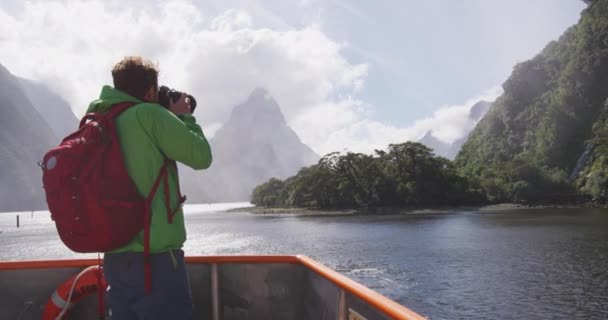 Landscape nature travel photographer tourist taking photo of Milford Sound and Mitre Peak in Fiordland National Park, New Zealand while on cruise ship boat tour — Stock Video