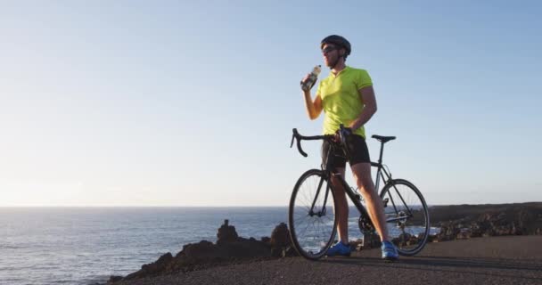 Napój sportowy - rowerzysta pijący z butelki wody na rowerze treningowym — Wideo stockowe