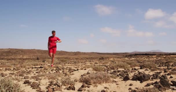 Бегущий мужчина - бегун, который смотрит на фитнес-умные часы во время растяжки — стоковое видео