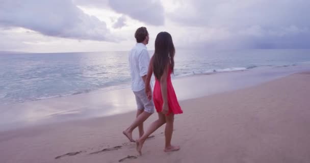 夕暮れ時にビーチを歩きながら手をつないでロマンチックなカップル — ストック動画