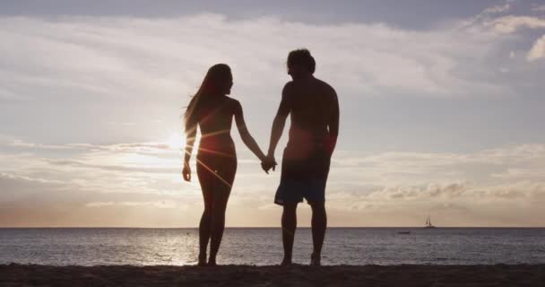 Luna de miel pareja apasionada tomados de la mano caminando en la playa — Vídeo de stock