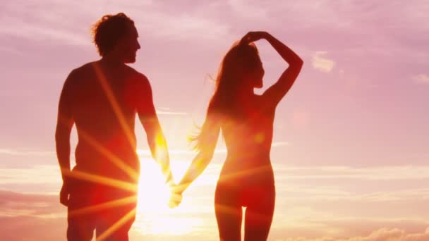 Puesta de sol pareja romántica cogida de la mano en la playa — Vídeos de Stock