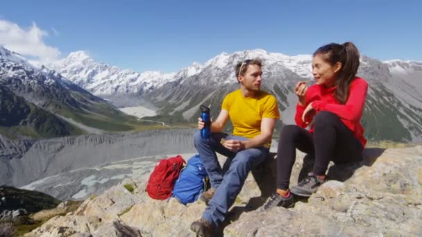 マウントクックによってニュージーランドの高山ハイキングで食べ物の休憩を取っているハイキングの人々 — ストック動画