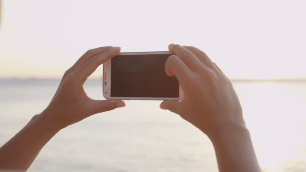 Foto del teléfono - Mujer tomando fotos usando teléfono inteligente playa puesta del sol — Vídeos de Stock