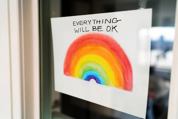 Коронавирус Rainbow рекламирует картину, висящую у окна дома, чтобы распространить позитив с сообщением EVERYTHING WILL OK на английском языке. Великобритания, США, Австралия. — стоковое фото