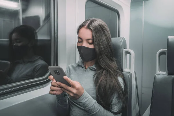 Openbaar vervoer forensen vrouw forensen 's nachts dragen gezichtsmasker rijden metro met behulp van mobiele telefoon. Aziatische passagier met gezicht coronavirus bedekking op trein woon-werkverkeer. — Stockfoto