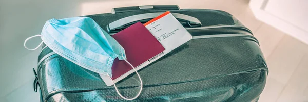 Ταξιδέψτε κατά τη διάρκεια του covid-19 με χειρουργική μάσκα προσώπου και τουριστικές αποσκευές πανοραμική πανό. Αεροπορικό εισιτήριο με διαβατήριο. — Φωτογραφία Αρχείου