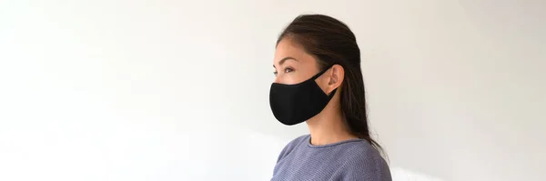 Ασιάτισσα που φοράει μαύρη υφασμάτινη μάσκα. Περιστασιακό τρόπο ζωής των νέων κατά τη διάρκεια της πανδημίας του κορωναϊού. Πορτρέτο της εθνοτικής κορίτσι μοντέλο με προστατευτικό κάλυμμα προσώπου πανό. — Φωτογραφία Αρχείου