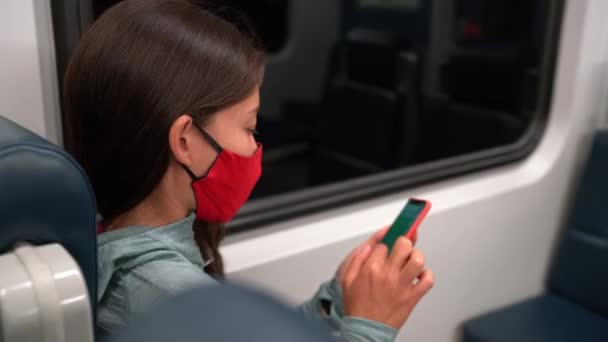 フェイスマスクコンセプト。公共交通機関で必須のマスクをしている女性。通勤電車。通勤中に顔を覆う携帯電話を使用して多人種の女性の乗客. — ストック動画