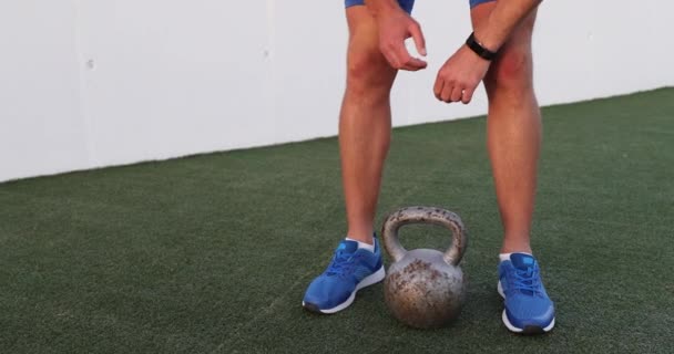 Fitness man starting fitness activity tracker lifting kettlebell — Stock Video