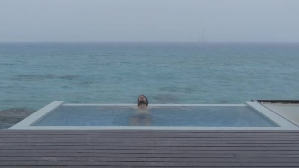Travel insurance concept. Vacation rain - funny video of holidays getaway raining away under heavy rainfall with relaxing happy man smiling in luxury pool, optimistic and not affected by bad weather. — 비디오