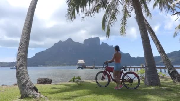 Perjalanan gaya hidup liburan. Perempuan bersepeda listrik alias eBike dalam perjalanan wisata di Bora Bora di Polinesia Perancis, Tahiti. — Stok Video