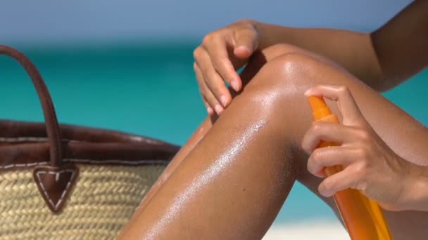 Frau sprüht Sonnencreme Sonnencreme am Strand - Bräunungsöl-Sprühflasche — Stockvideo