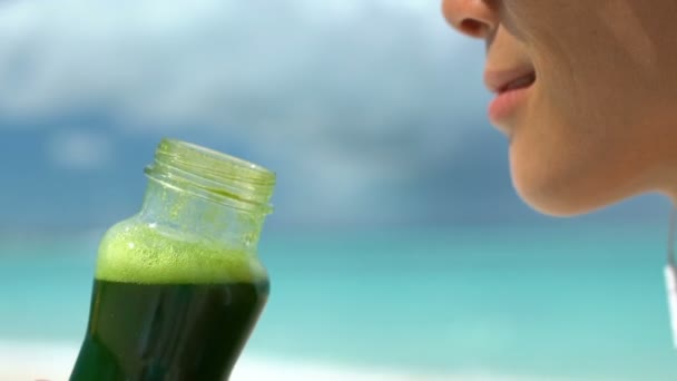 Γυναίκα πίνοντας πράσινο Smoothie λαχανικών στην παραλία - Υγιεινή διατροφή Απεξάρτηση χυμό — Αρχείο Βίντεο