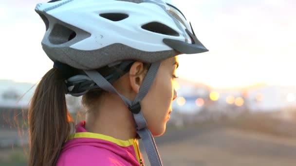 Kvinnlig cyklist med cykel hjälm tittar på solnedgången - Porträtt av sportig kvinna — Stockvideo