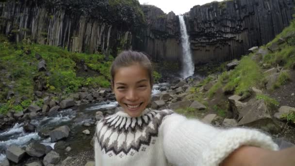Mulher soprando beijo contra a cachoeira Svartifoss — Vídeo de Stock