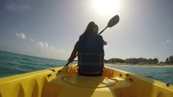 Женщина плавает на каяке в море в солнечный день — стоковое видео